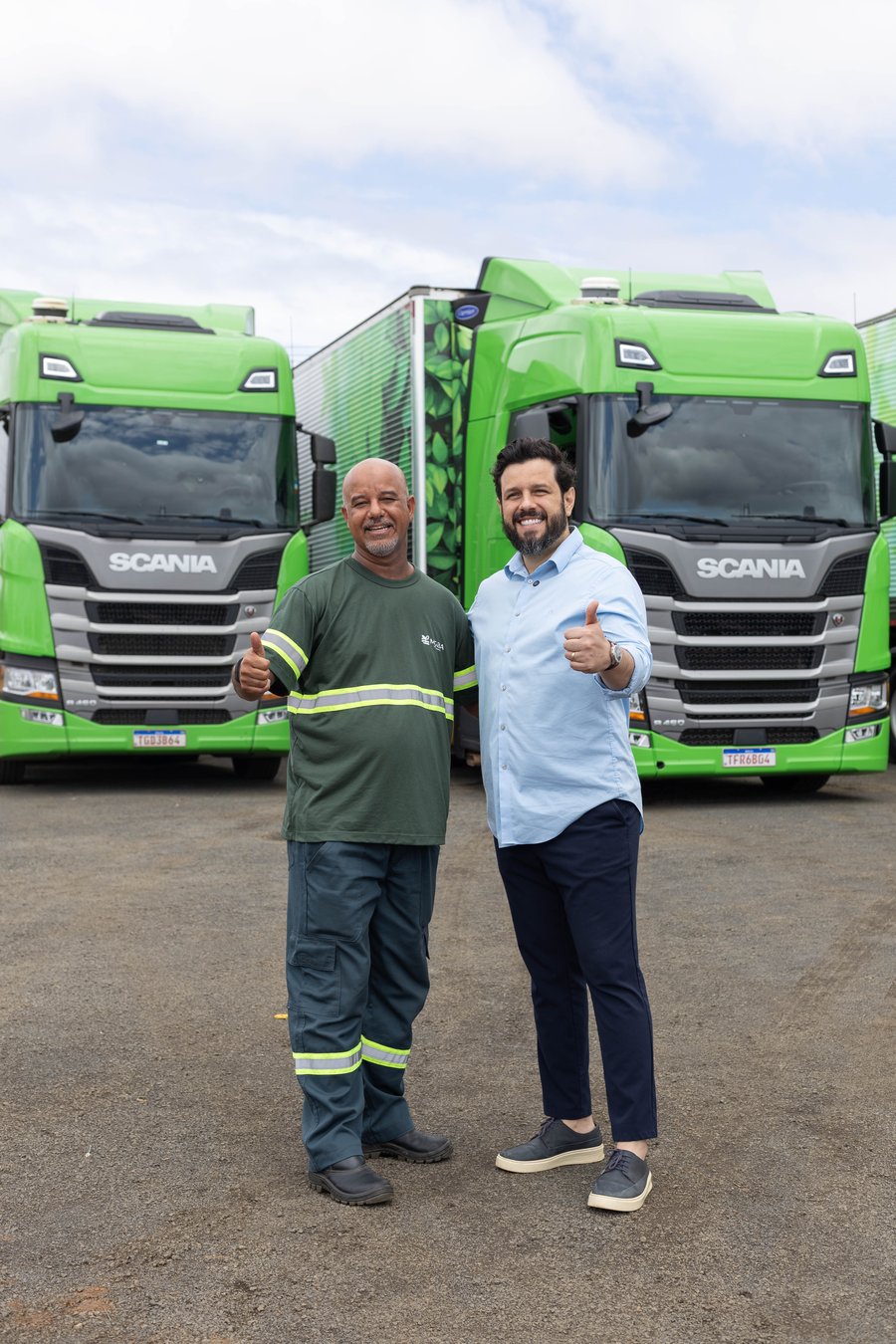 Motorista e liderança da MGBA Transportes em frente à frota verde